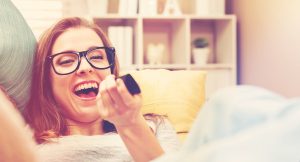 A young woman laughs while watching TV