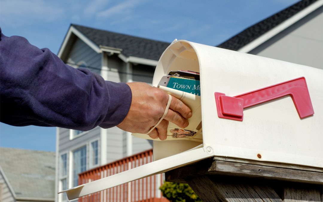 A person takes mail out of their mailbox.